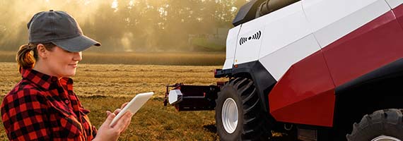 Female farmer with tablet next to machine